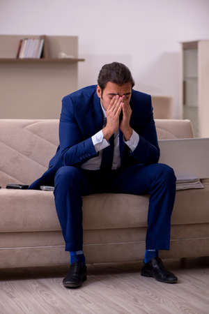 Young male employee working from home in pandemic conceptの写真素材