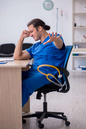 Young male doctor being unhappy after night shiftの写真素材