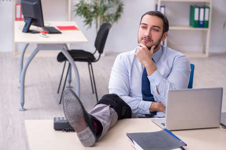 Young leg injured employee working in the officeの写真素材