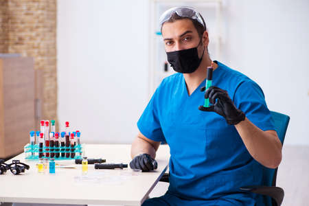 Young male biochemist testing blood samples in pandemic concept