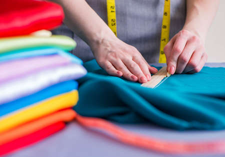 Woman tailor working on a clothing sewing stitching measuring fa