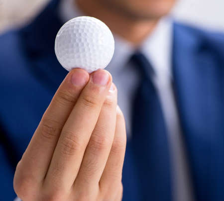 Young businessman with golf ball working in officeの写真素材