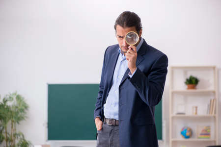 Young male teacher in front of green boardの写真素材