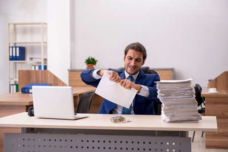 Young man employee reading contract at workplaceの写真素材