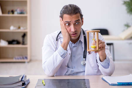 Young male doctor in time management concept