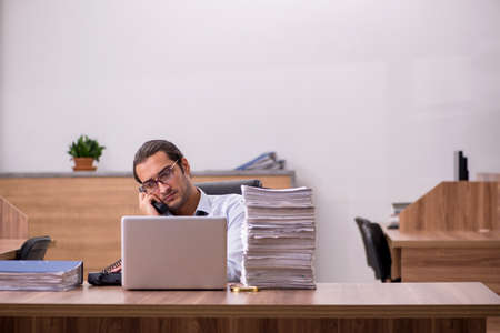 Young male employee unhappy with excessive work in the officeの写真素材