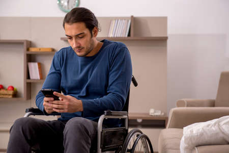 Young man in wheel-chair suffering at homeの写真素材