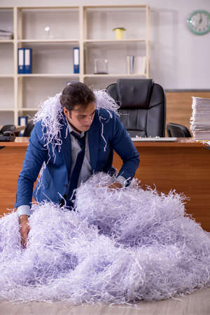 Young male employee and a lot of cut papers in the officeの写真素材
