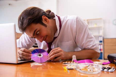 Young drug addicted male employee working in the office