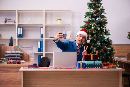 Young male employee celebrating Christmas at workplaceの写真素材