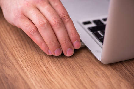 Young male employee inserting flash drive into laptop