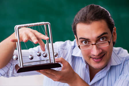 Young male teacher physicist in front of blackboardの写真素材