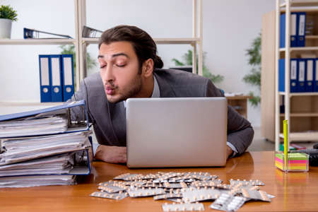 Young male sick employee suffering at workplaceの写真素材