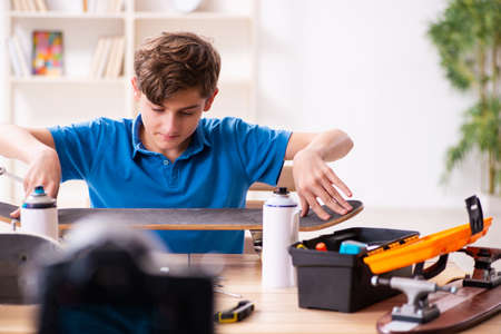 Boy repairing skateboard and recording video for his blogの写真素材