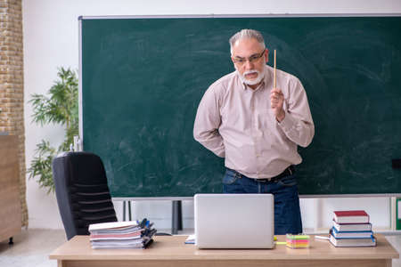 Old male teacher sitting in the classroomの写真素材