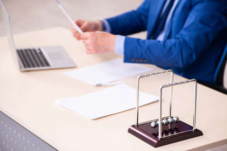 Old male employee businessman and meditation balls on the deskの写真素材