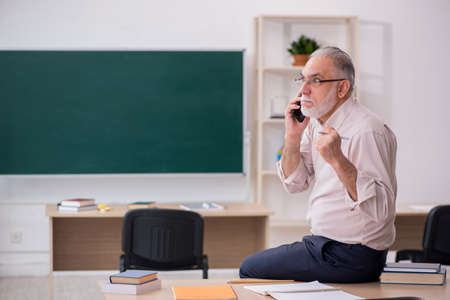 Old male teacher in front of blackboardの写真素材