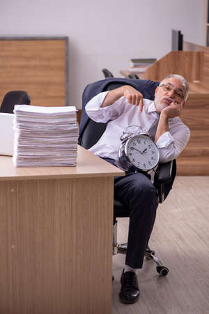Old male employee in time manegement conceptの写真素材