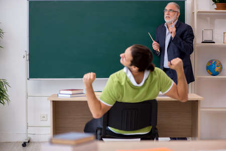 Aged teacher and young male student in the classroom
