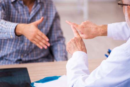 Young male patient visiting aged male doctorの写真素材