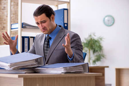 Young businessman employee unhappy with excessive work in the o