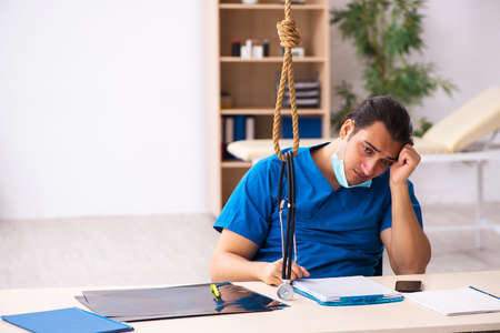 Young male doctor committing suicide at workplace