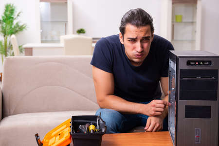 Young man repairing computer at homeの写真素材