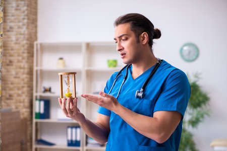 Young male doctor in time management concept