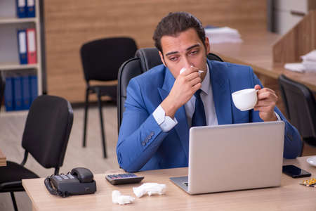 Young sick businessman employee suffering at workplaceの写真素材