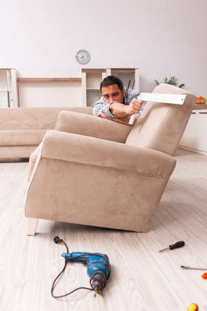 Young male carpenter repairing furniture at homeの写真素材