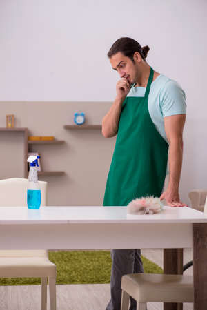 Young male contractor cleaning the houseの写真素材