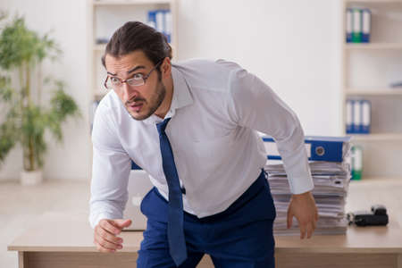 Young businessman unhappy with excessive work in the officeの写真素材