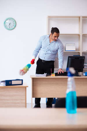 Young male employee cleaning office during pandemicの写真素材