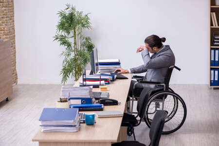 Young male enployee in wheel-chair at workplaceの写真素材