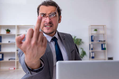 Young male employee unhappy with excessive work in the officeの写真素材