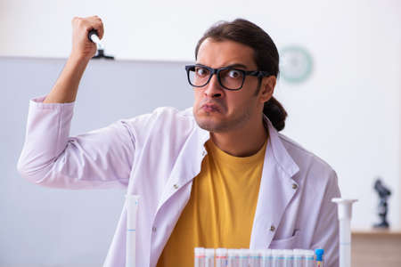 Young male chemist teacher in the classroom