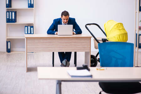 Young male employee looking after kid at workplaceの写真素材