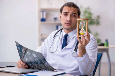 Young male doctor in time management conceptの写真素材