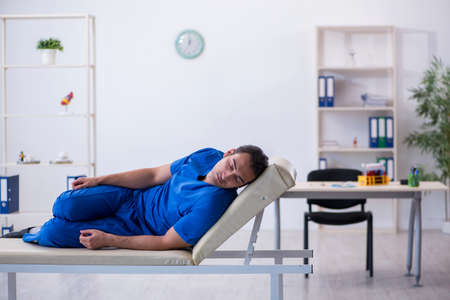 Young male doctor being extremely tired in the clinicの写真素材