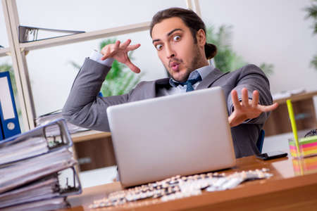 Young male sick employee suffering at workplaceの写真素材