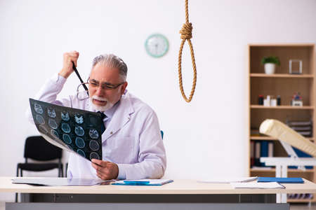 Old male doctor committing suicide at workplace