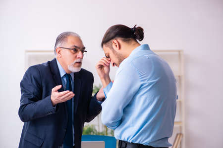 Old boss and his young assistant in the officeの写真素材