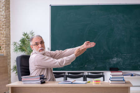 Old male teacher sitting in the classroomの写真素材