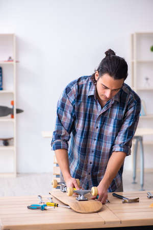 Young man repairing skateboard at workshopの写真素材