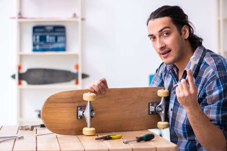 Young man repairing skateboard at workshopの写真素材