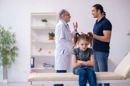 Young father and his daughter visiting old male doctorの写真素材