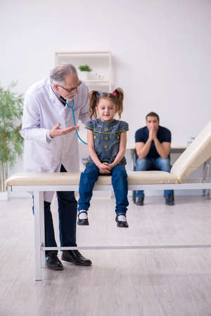 Young father and his daughter visiting old male doctorの写真素材