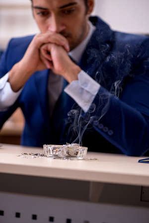 Young male employee burning papers in the officeの写真素材
