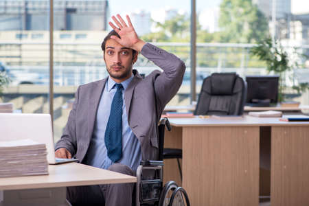 Young male employee in wheel-chair working in the officeの写真素材