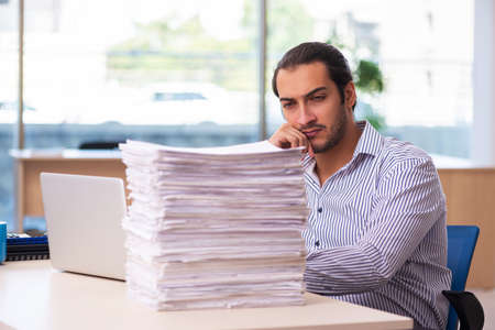 Young male employee unhappy with excessive work in the office
